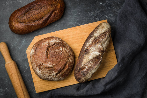 Rustic bread on dark background. Flat lay. - Фото, изображение