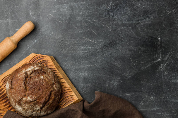 Rustic bread of whole wheat grains on dark background with copy space. Flat lay. - Foto, imagen