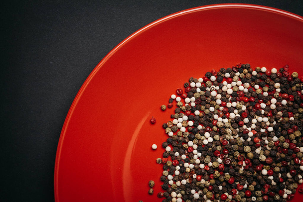 red plate with a mixture pepper on a dark background - Foto, Imagen