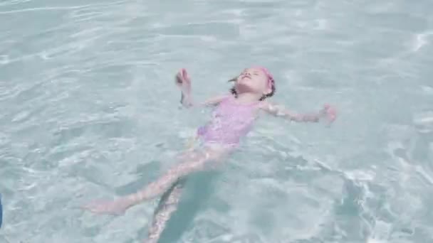 Kislány szórakozás úszás szabadtéri medence a nyáron. - Felvétel, videó