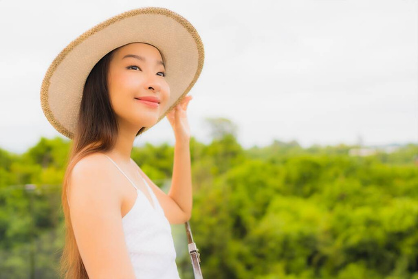 Portriat mooie jonge aziatische vrouw gelukkig glimlach rond balkon met uitzicht op zee achtergrond - Foto, afbeelding
