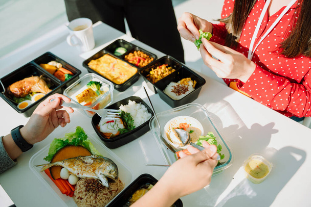 Top view - mensen eten graag samen gezond voedsel op witte tafel. Voedsellevering. Lunchbox set. - Foto, afbeelding