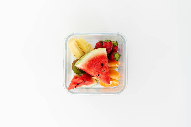 Vista superior de la fruta en tazón de cristal, sandía, piña, fresa, kiwi. Aislamiento en blanco
. - Foto, imagen