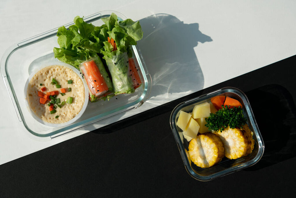 Κάτοψη του φρέσκου ανοιξιάτικου ρολού με σάλτσα αυγού και ψητά λαχανικά καλαμπόκι και καρότο πατάτας σε ποτήρι περιέχουν κουτί σε μαύρο και άσπρο φόντο μοτίβο. - Φωτογραφία, εικόνα