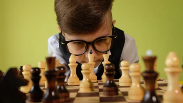 Child playing chess at table. Little boy with glasses developing chess strategy, play board game with friend. - Footage, Video