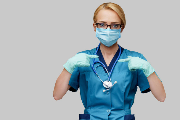 medical doctor nurse woman with stethoscope wearing protective mask and rubber or latex gloves showing at herself - Zdjęcie, obraz