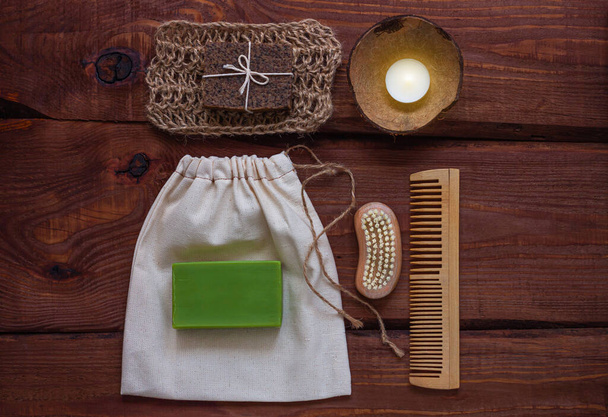 Spa wellness concept, natural coffee scrub, green conifer soap, eco bag, candle in coconut shell, peeling brush, ecological wooden haircomb.Dayspa product set. Zero waste bathroom accessories flat lay - Photo, Image