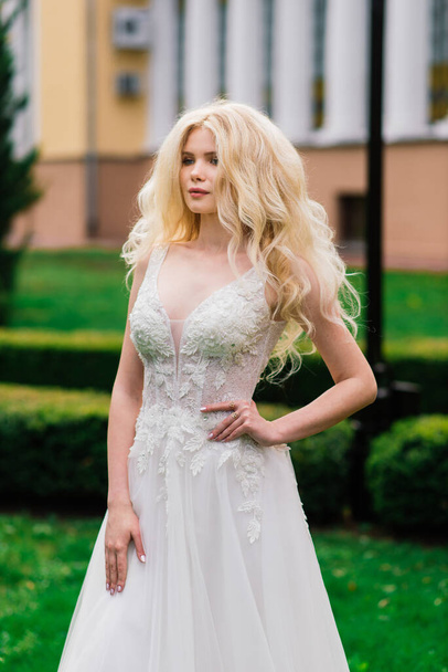 Minsk, Belarus - 05.05.2020. Young attractive blonde bride with curly hair walking in the park and smiling, concept wedding - Zdjęcie, obraz