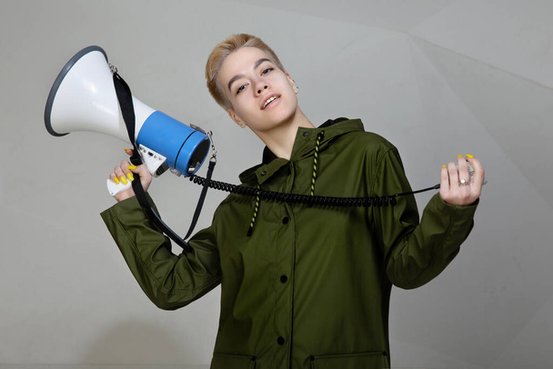 girl with a megaphone on a gray background. stylish clothes - Photo, Image