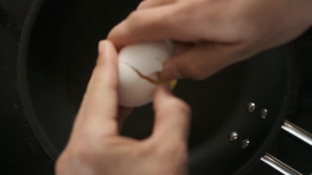 Slow Motion Shot of Hands Cracking an Egg on Black Pan - Filmagem, Vídeo