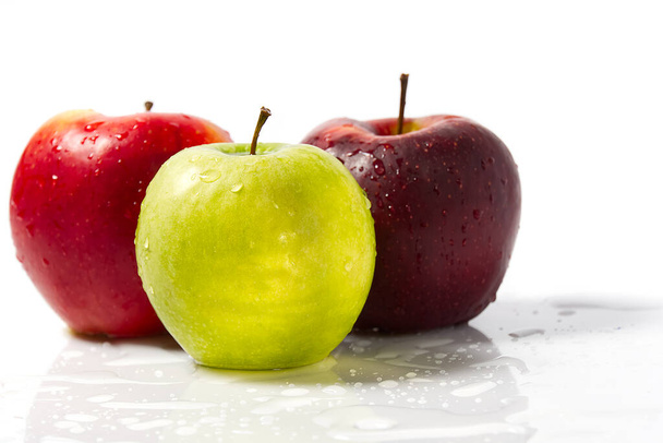 Три яблука з краплями води. Смачні апетитні красиві свіжі зелені та червоні яблука на білому тлі
. - Фото, зображення