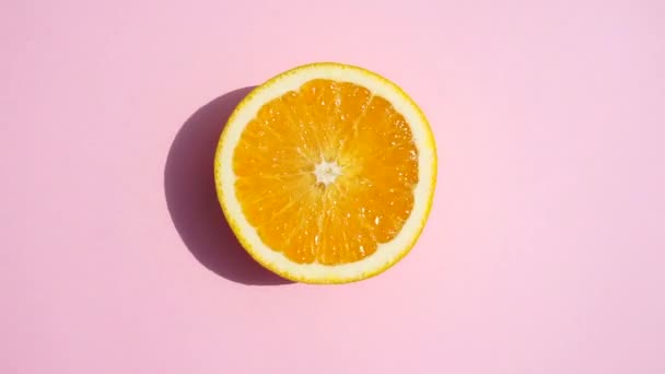 Girando naranja sobre un fondo rosa aislado. Naranja amarillo fresco jugoso en la luz del sol del verano sobre un fondo pastel de colores. Jugos frescos, frutas, vitaminas y concepto de verano
. - Metraje, vídeo