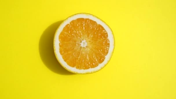 Rotating orange on a yellow background isolate. Juicy fresh yellow orange in the summer sunlight on a colored pastel background. Fresh juices, fruits, vitamin and summer concept. - Filmmaterial, Video