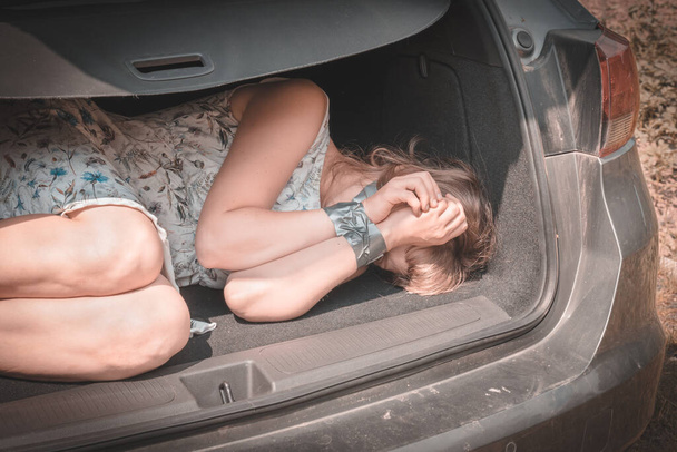  Woman with tied hands inside car trunk - kidnapping - Фото, изображение