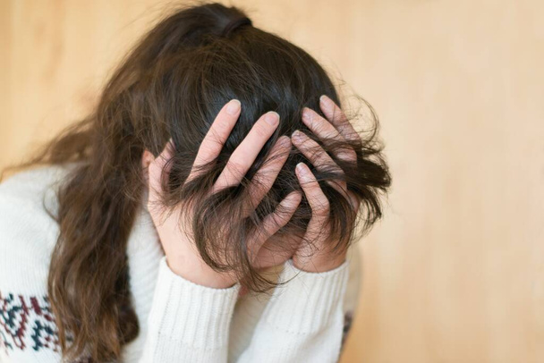 Retrato emocional de una joven triste sosteniendo su cabeza en las manos
 - Foto, Imagen