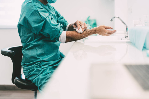 Хірург миє руки перед операційним пацієнтом у лікарні - медичний працівник готується до боротьби з пандемією коронавірусу - концепція охорони здоров'я та гігієни
 - Фото, зображення