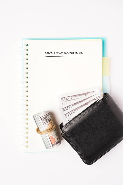 Gastos mensuales en un cuaderno con billeteras en el lateral
 - Foto, imagen