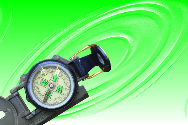 круглий компас як символ туризму, подорожей та активного відпочинку на зеленому фоні
 - Фото, зображення