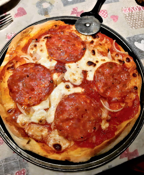 suggestiva immagine di una pizza fatta in casa con salumi piccanti, pomodori e mozzarella - Foto, immagini