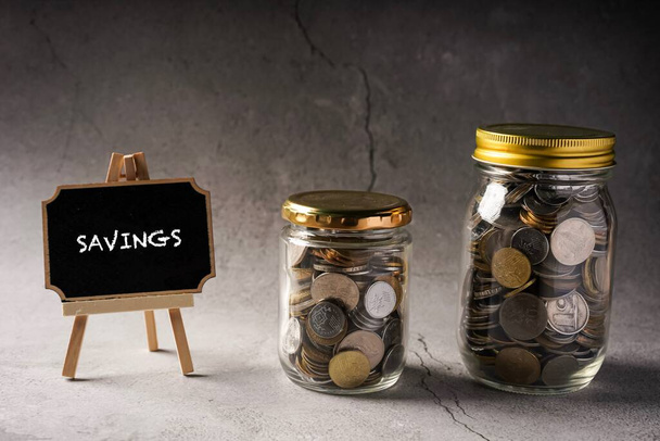 Формулировки сбережений на доске с монетами в стеклянной банке
. - Фото, изображение
