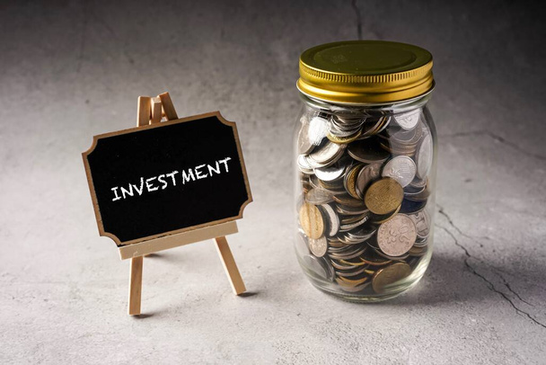 Investiční výrazy na tabuli s mincemi ve sklenici. - Fotografie, Obrázek
