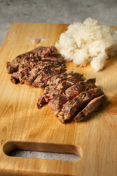 Стейк з яловичини Ваг'ю з липким рисом на дерев'яній обробній дошці
 - Фото, зображення