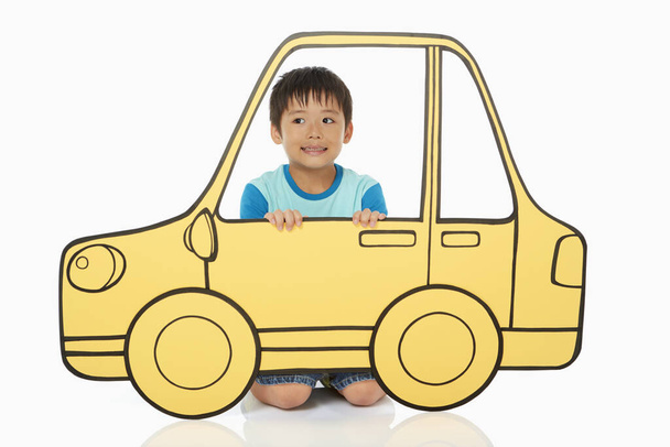 Boy holding up a cardboard car - Фото, изображение