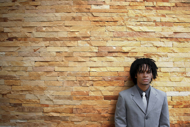 An African American man in business suit leaning against a wall - Valokuva, kuva