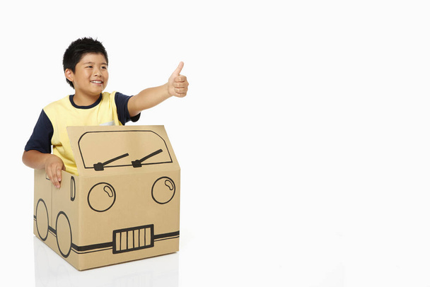 Boy in cardboard bus showing hand gesture - Valokuva, kuva