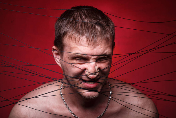 Foto de homem louco em fios pretos no fundo vermelho
 - Foto, Imagem