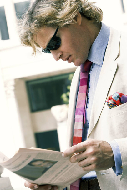 A guy in business suit and sunglass reading newspaper - Zdjęcie, obraz