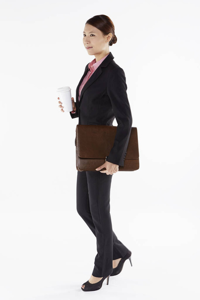 Businesswoman holding a disposable cup and a briefcase - 写真・画像