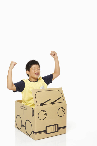 Boy sitting in a cardboard bus, cheering - Фото, изображение