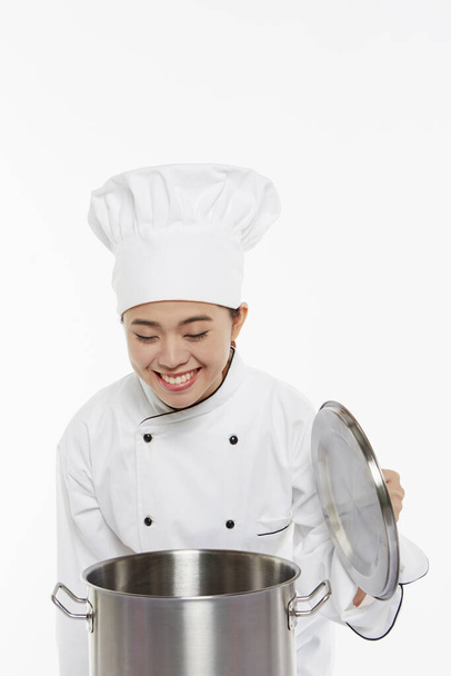 Vrouwelijke chef ruikt eten uit de pot - Foto, afbeelding
