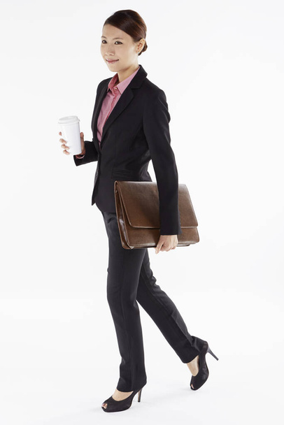 Businesswoman holding a disposable cup and a briefcase - Foto, imagen