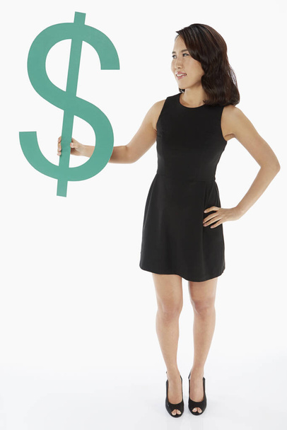 Woman holding up a dollar sign - Photo, image