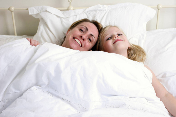 女と娘がベッドの上に横になって - 写真・画像