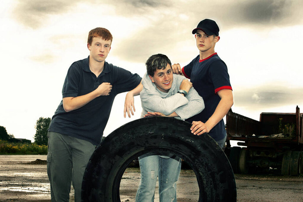 Three boys posing with a big tyre - Foto, Imagem