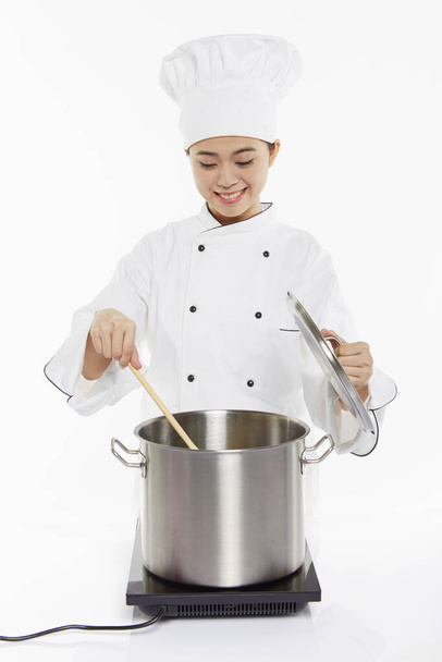 Female chef cooking and stirring - Zdjęcie, obraz