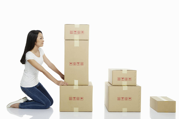 Woman arranging a stack of cardboard boxes - Zdjęcie, obraz