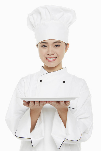 Female chef holding up a tray - Zdjęcie, obraz
