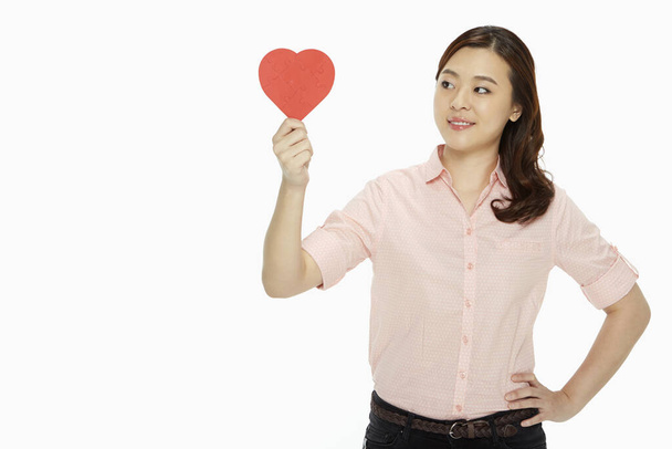 Cheerful woman holding up a red heart - 写真・画像