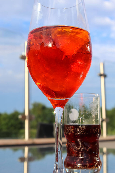 Cocktails d'été orange rafraîchissants au cola et glace sur fond de ciel bleu.  - Photo, image
