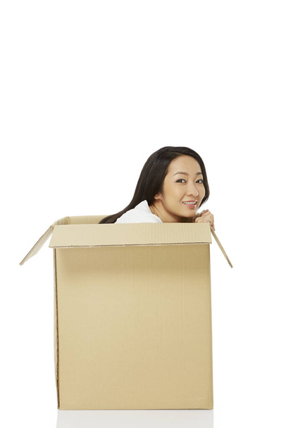 Woman sitting inside of a cardboard box, smiling - Foto, Imagem