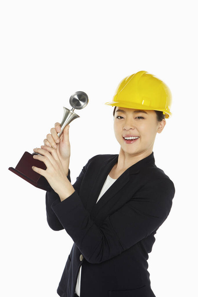 Happy female architect holding up a trophy - Zdjęcie, obraz