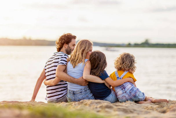 Zdjęcie czteroosobowej rodziny spędzającej dzień na plaży. - Zdjęcie, obraz