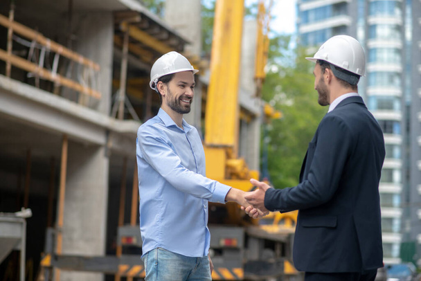 Building supervisor and foreman greeting, shaking hands with each other on building site - Valokuva, kuva