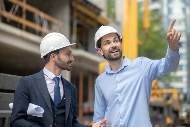 Foreman pointing his hand, showing something to building supervisor - Φωτογραφία, εικόνα