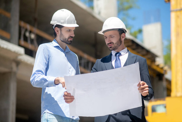 Building supervisor holding blueprint, discussing it with foreman - Photo, Image