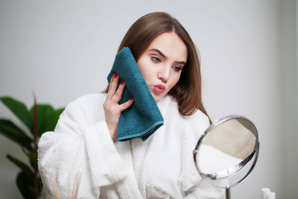 Очищение кожи лица, молодая женщина, держащая полотенце рядом с кожей лица после мытья лица
 - Фото, изображение